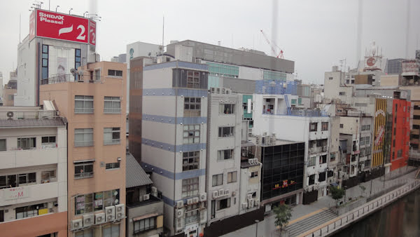 a row of slim buildings along the Dotonbori canal on an overcast day
